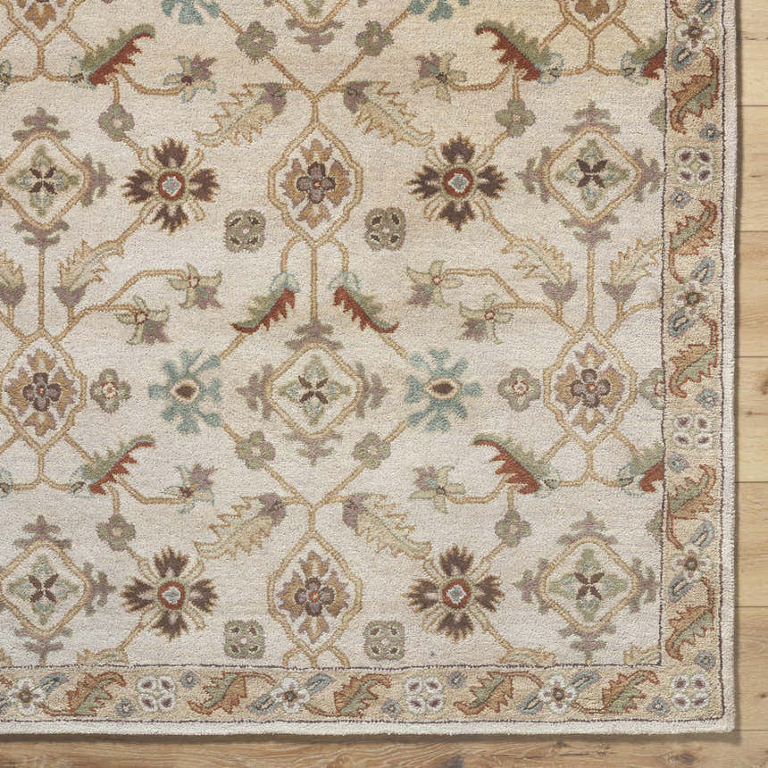 Close-up of the Postelle Wool Rug. Hand-tufted rug with a traditional floral pattern in brown, sage, and tan on a cream background. Corner