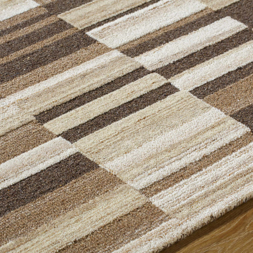 Close-up of the hand-tufted Amrita Beige Area Rug. Features a geometric block pattern in beige, cream, tan, and brown wool. Texture