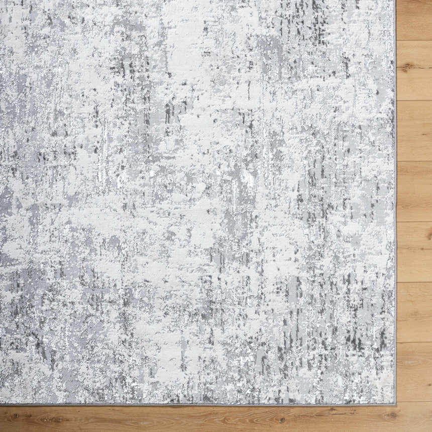Close-up of the Avital Area Rug, a contemporary rug in black, charcoal, gray, and white, on a wood floor. Corner