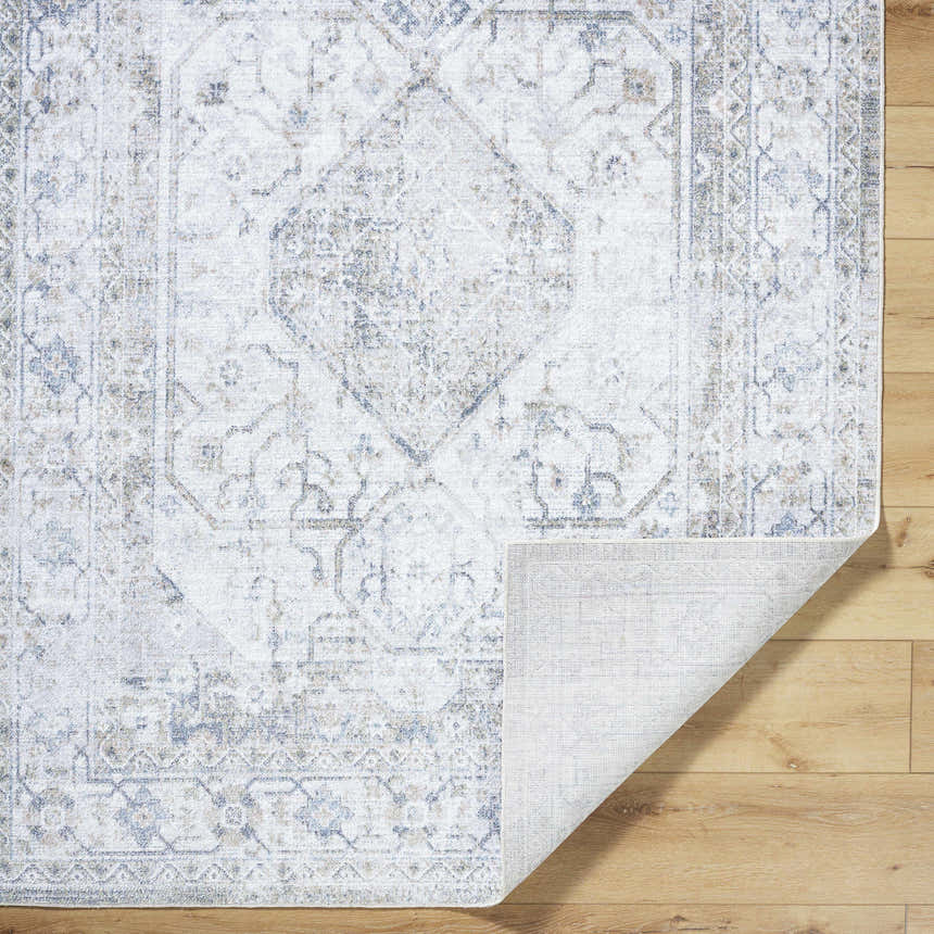 Close-up of the Annlea Washable Area Rug. Farmhouse style rug in blue, sage, and white with traditional design. Fold