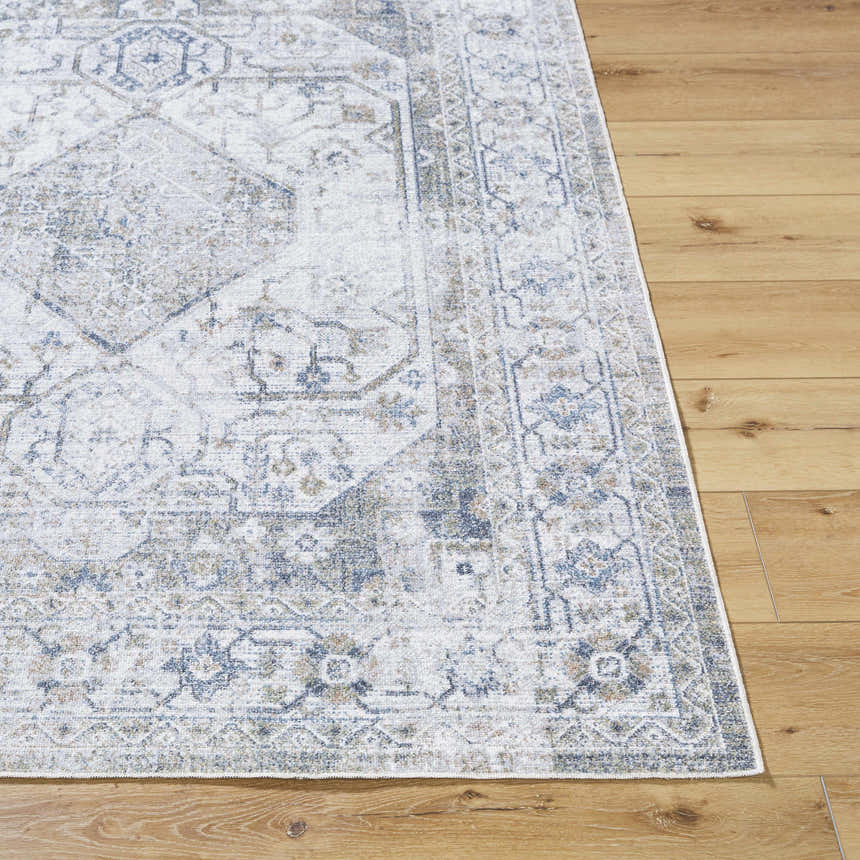 Close-up of the Annlea Washable Area Rug. Traditional rug design in blue, sage, and white on a wood floor. Front