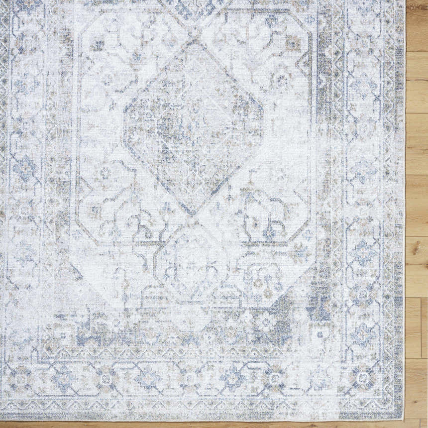 Close-up of the Annlea Washable Area Rug. Farmhouse style rug in blue, sage, and white with a traditional, machine-woven pattern. Corner