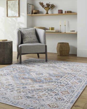 Living room scene with gray armchair and Agaton Blue Washable Area Rug with traditional blue, orange, and white pattern. Roomscene-Rectangle