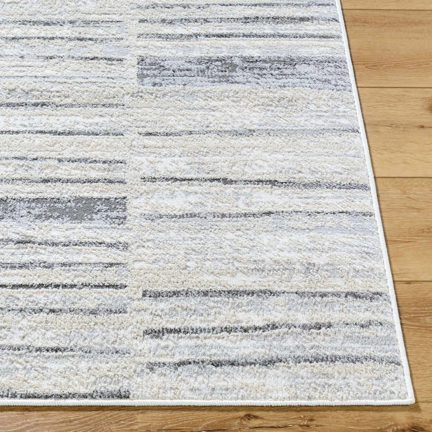 Close-up of the Allete Broken-Striped Area Rug. Ash, light silver, and silver gray stripes on a soft, textured rug. Front