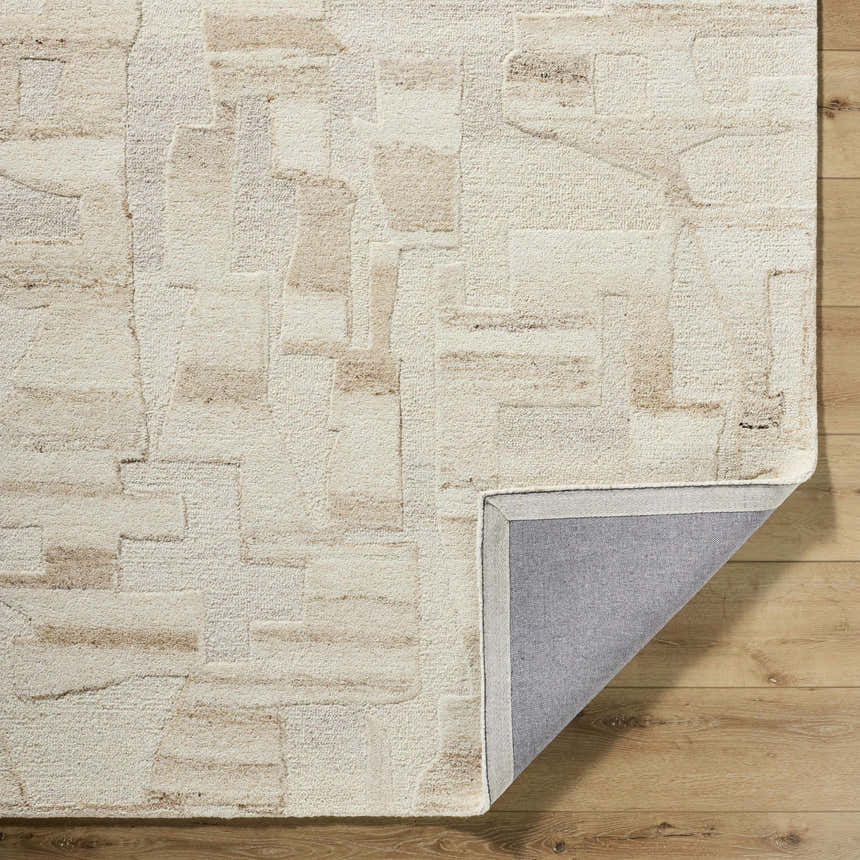 Close-up of the Aintza Area Rug. Hand-tufted wool rug in beige, cream, ivory, and tan with a geometric pattern. Fold