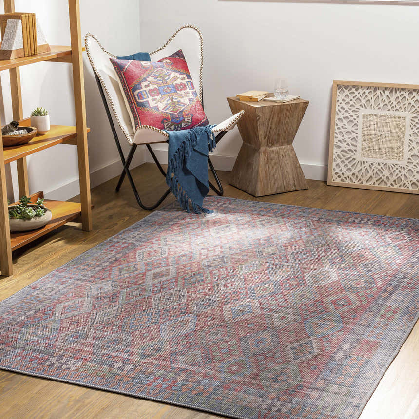 Living room scene with a Ranao Washable Area Rug in blue, red, and green, styled with a butterfly chair and wood accents. Roomscene-Rectangle