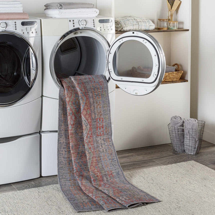 Laundry room scene with Ranao Washable Area Rug coming out of dryer. Farmhouse style with gray wood-look floors and white appliances. Washing-Machine