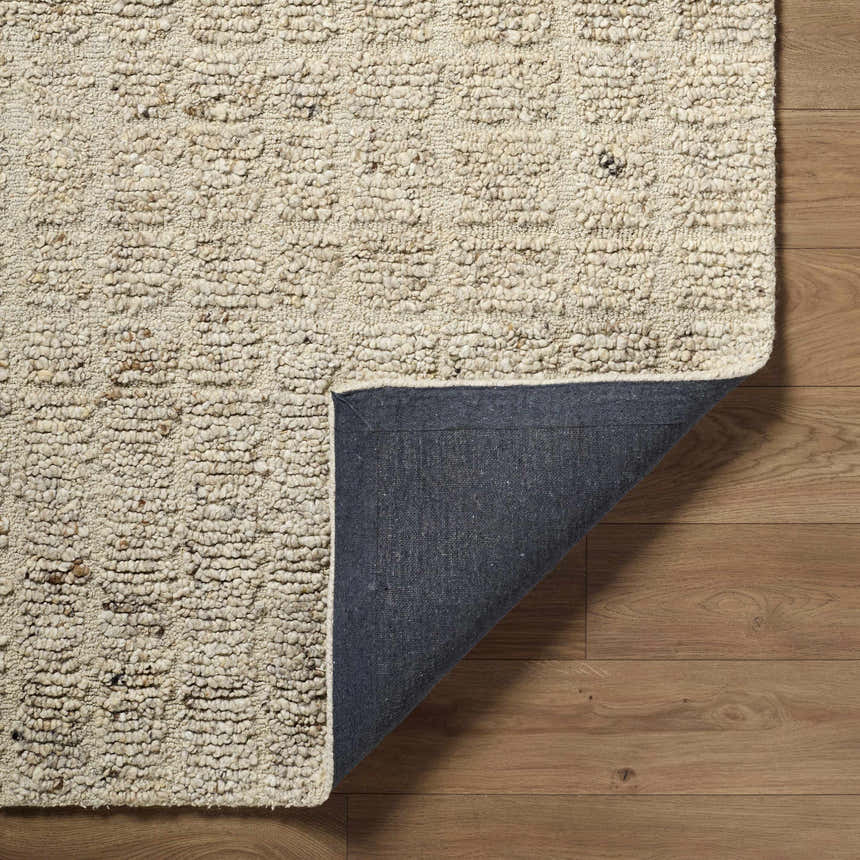 Close-up of the hand-tufted Asahel Ivory Area Rug. Farmhouse style wool rug with subtle geometric pattern and gray backing. Fold