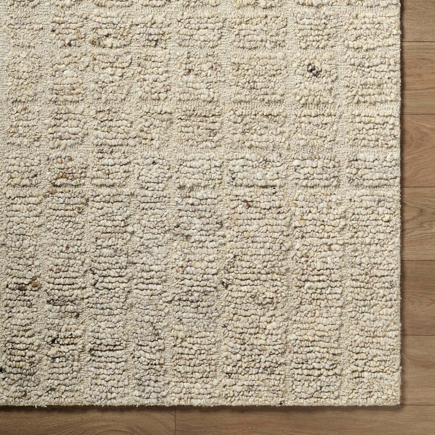 Close-up of the hand-tufted Asahel Ivory Area Rug, a farmhouse style rug made of 100% wool with a subtle geometric pattern. Corner
