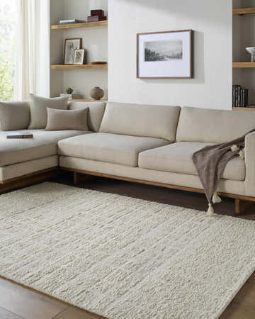 Living room scene with a cream sectional sofa and the Asahel Cream Area Rug. Roomscene-Rectangle