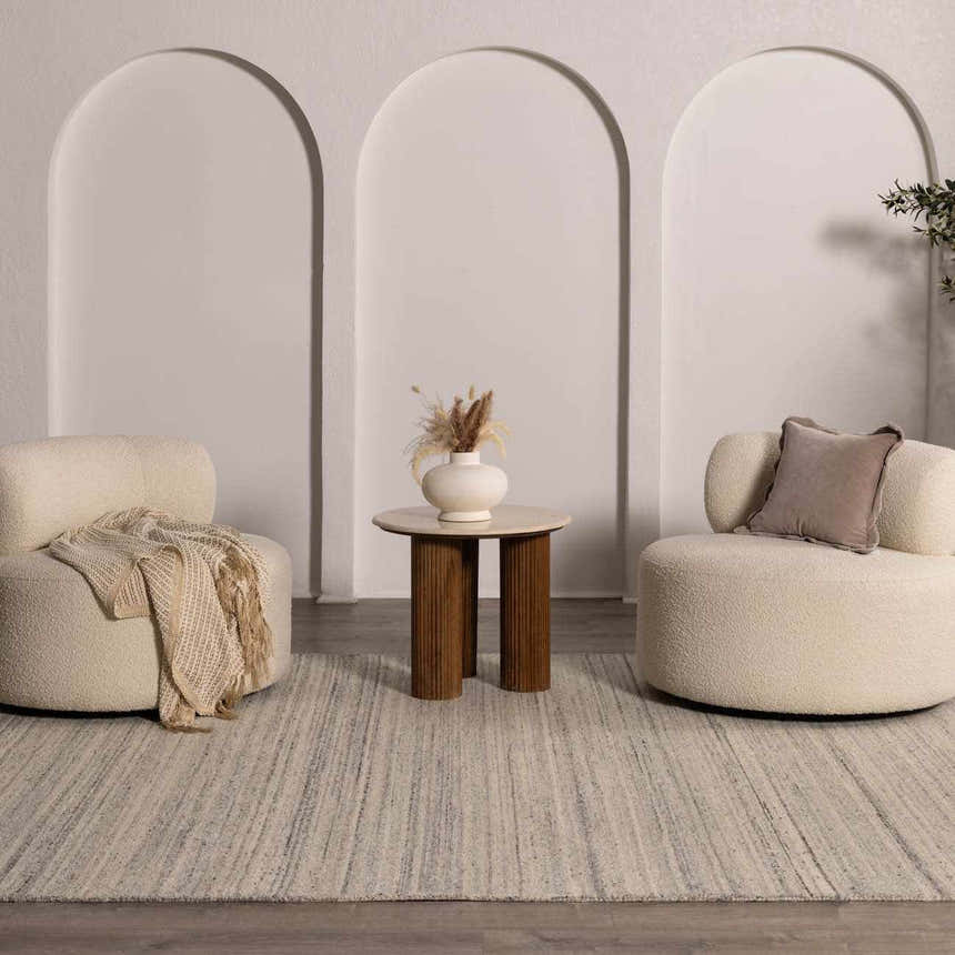 Neutral living room scene with two chairs, a round table, and the Capote Charcoal Area Rug. Roomscene-Rectangle