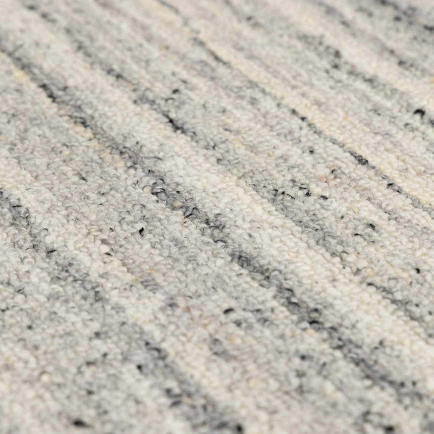 Close-up of the hand-tufted Capote Charcoal Area Rug. Shows wool texture and charcoal, ivory, and slate gray colors. Texture