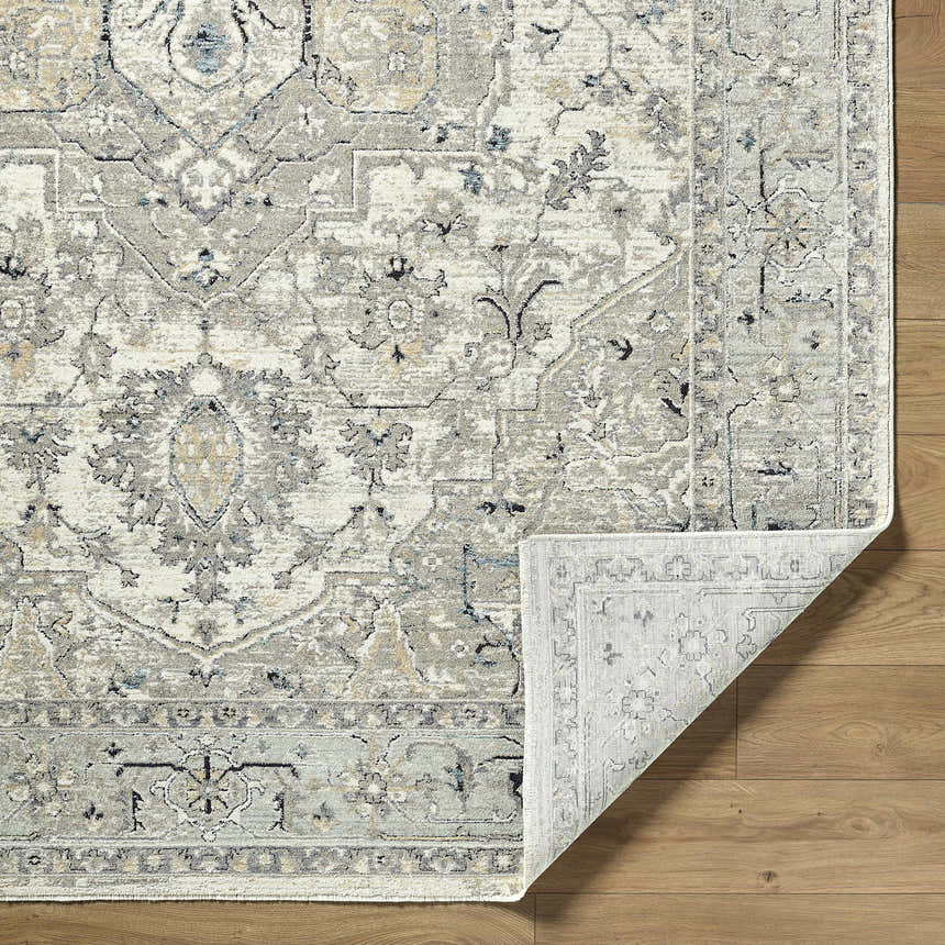 Close-up of the Ayzize Ivory Area Rug showing its farmhouse traditional design, charcoal, ivory, and blue colors, and soft texture. Fold