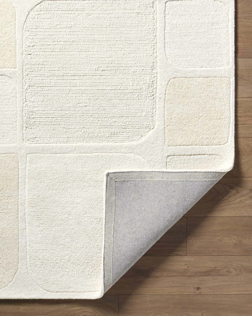Close-up of the hand-tufted Antwan Area Rug, showing the geometric design, wool texture, and backing. Beige, cream, ivory, and tan tones. Fold