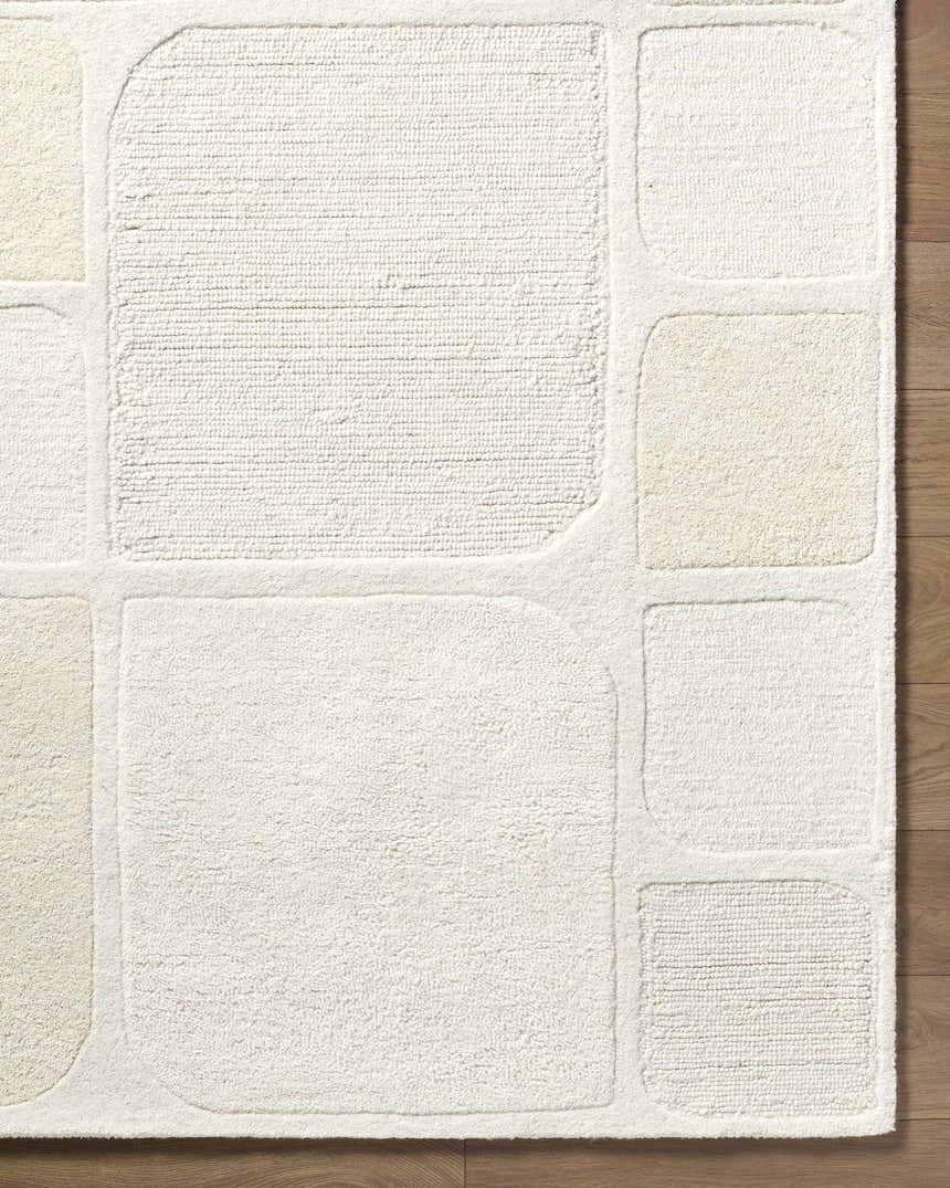 Close up of the hand-tufted Antwan Area Rug. Beige and cream geometric pattern on a soft, wool texture. Corner