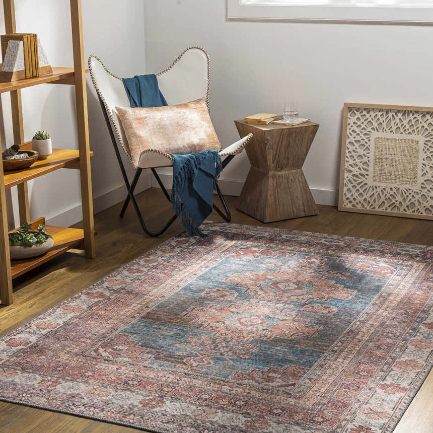Living room scene with Baltinglass Rust & Blue Washable Area Rug, white chair, and wooden side table. Farmhouse style. Roomscene-Rectangle
