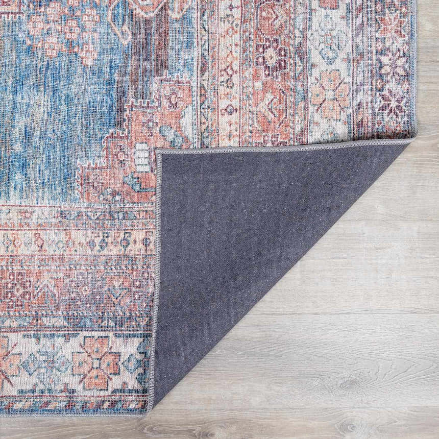 Close-up of the Baltinglass Rust & Blue Washable Area Rug showing its traditional oriental pattern and chenille-polyester texture. Fold