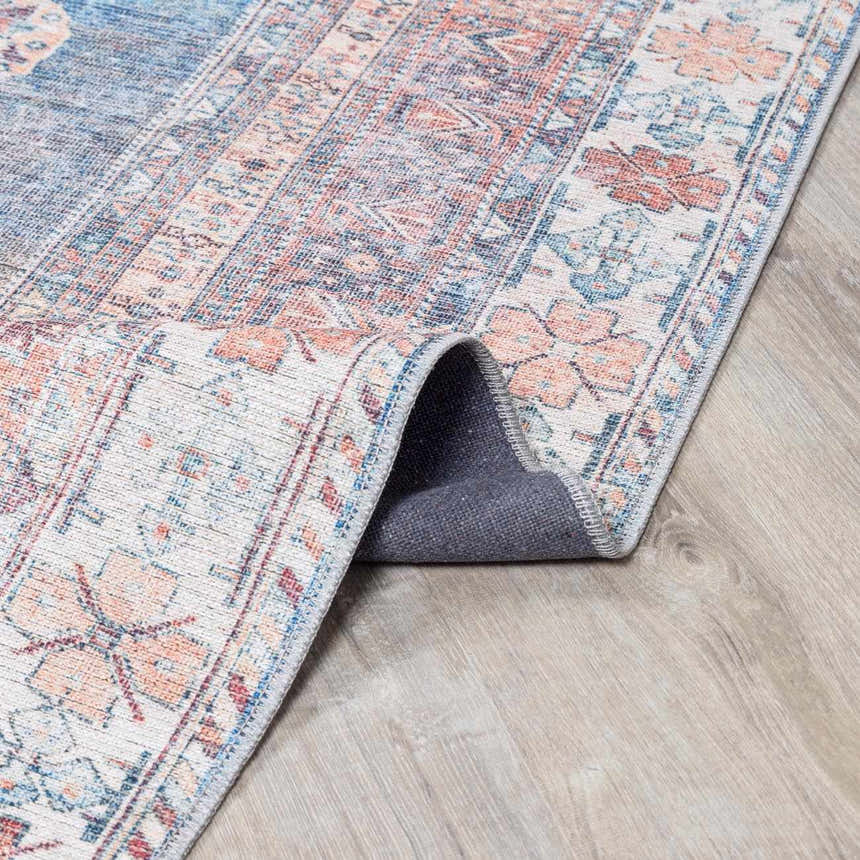 Close-up of the Baltinglass Rust & Blue Washable Area Rug, showing its traditional floral pattern and soft chenille texture. Fold