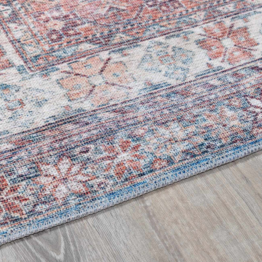 Close-up of the Baltinglass Rust & Blue Washable Area Rug, showing its traditional, oriental-inspired pattern and colors. Corner