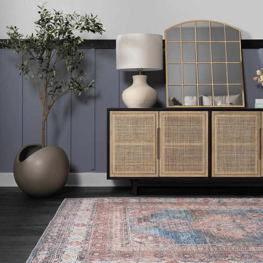 Entryway with a Baltinglass Rust & Blue Washable Area Rug, dark floors, and a rattan cabinet with a mirror. Roomscene-Rectangle