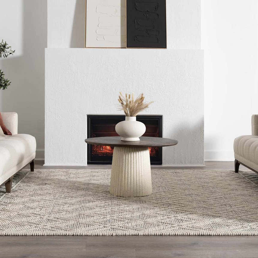 Living room scene with a geometric ivory and black Ramsbury Wool Area Rug under a round coffee table. Roomscene-Rectangle
