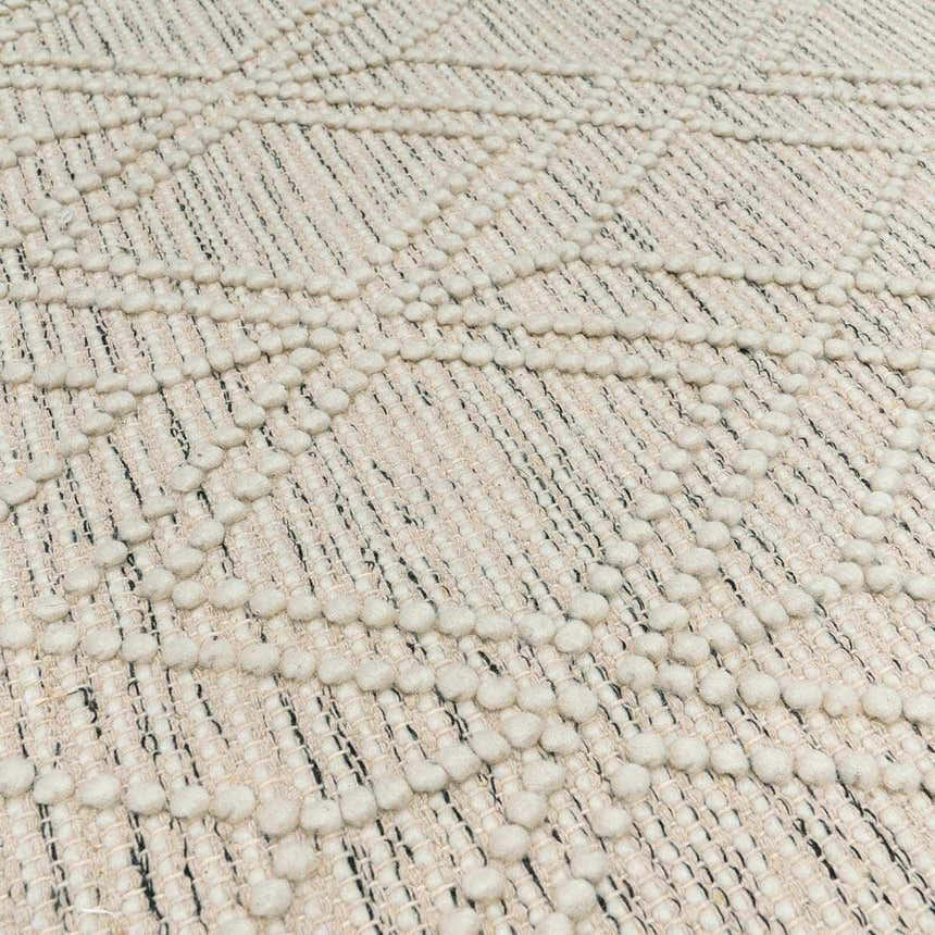 Close-up of the Ramsbury Wool Area Rug. Ivory rug with a geometric pattern and textured, raised dots. Hand woven. Texture
