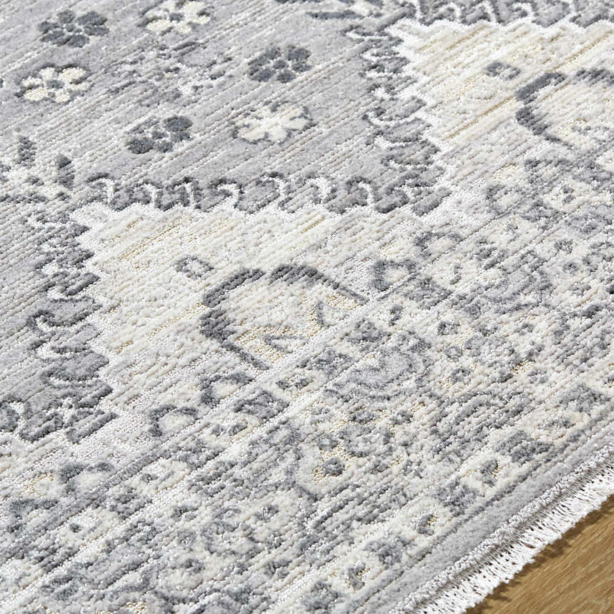 Close-up of the Aoibhe Area Rug. Traditional ivory, medium gray, and slate gray floral pattern. Machine woven texture. Texture