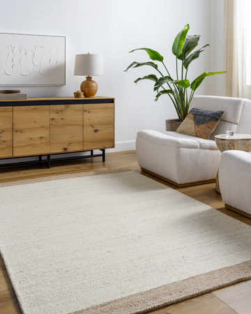 Living room scene with beige Amabel Area Rug, ivory chairs, and wood accents creating a warm, neutral space. Roomscene-Rectangle