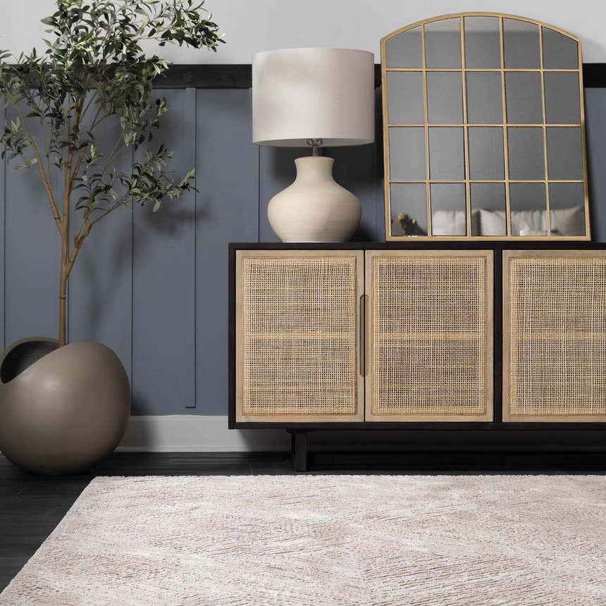 Living room scene with a beige Garza Diamond Textured Washable Rug, dark wood floors, and a modern cabinet with a lamp and mirror. Roomscene-Rectangle
