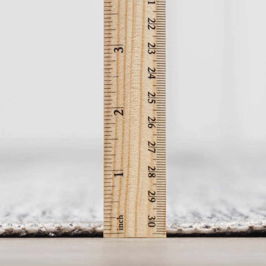 Close-up of the Barny Gray Blue Washable Rug pile height, showing its soft, low-pile texture with a ruler. Pile