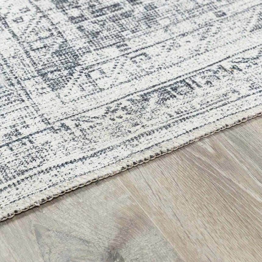 Close-up of the Barny Gray Blue Washable Rug, showcasing its traditional pattern and soft texture on a wood floor. Pile