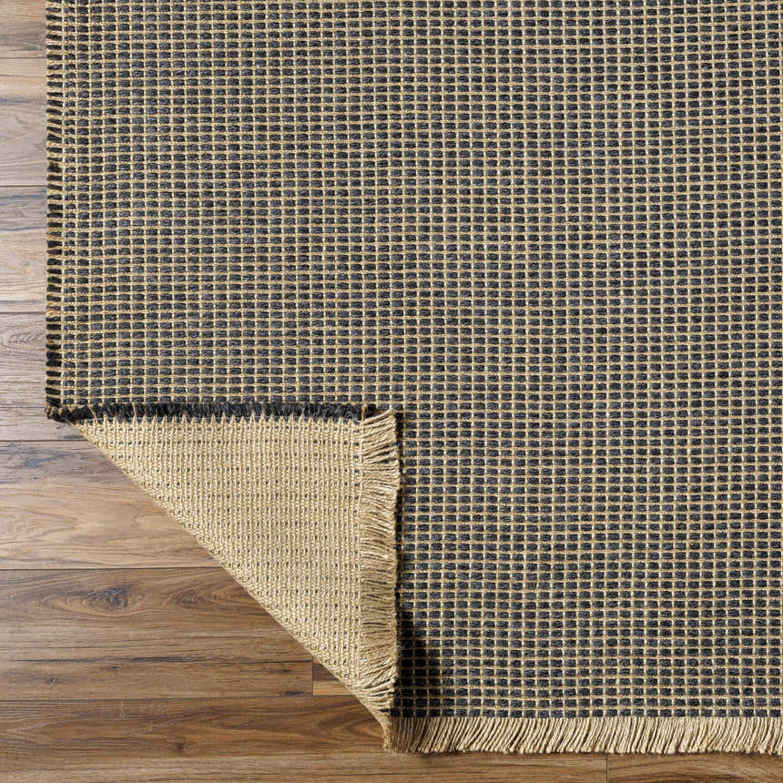 Close-up of the Kimi Machine Woven Becki Owens x LIVABLISS rug. Black and light brown jute with a grid pattern and fringed edge. Fold