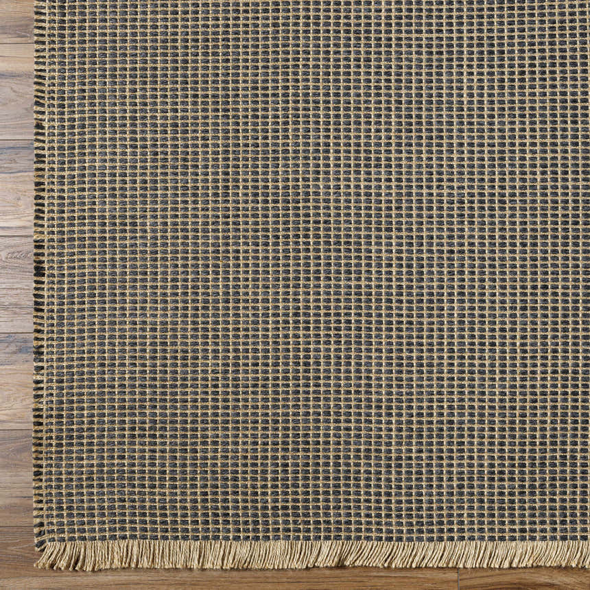 Close-up of Kimi Becki Owens x LIVABLISS BOKM-2305 Area Rug. Black and light brown jute rug with woven grid pattern and fringe. Corner