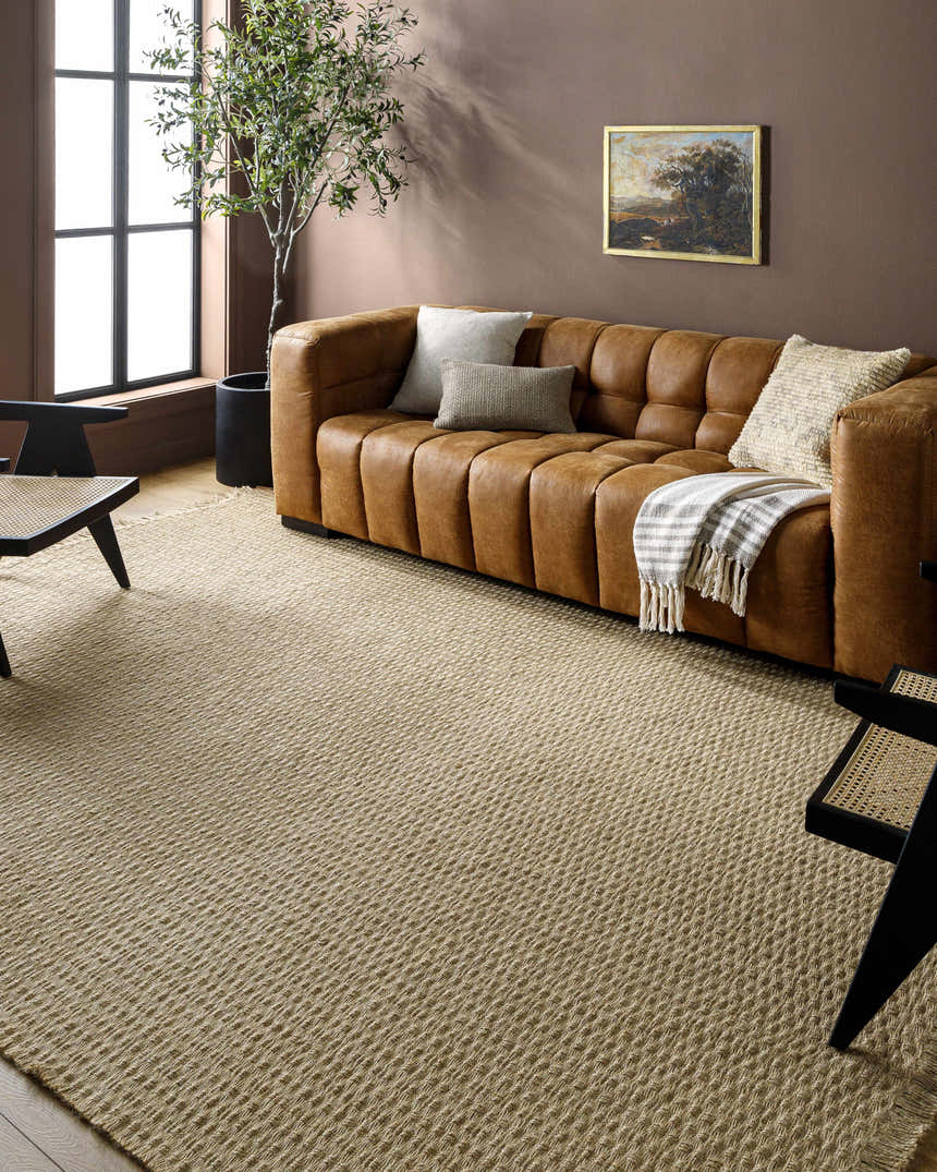 Living room scene with a light brown Kimi Machine Woven Becki Owens x LIVABLISS area rug, leather sofa, and brown walls. Roomscene-Rectangle