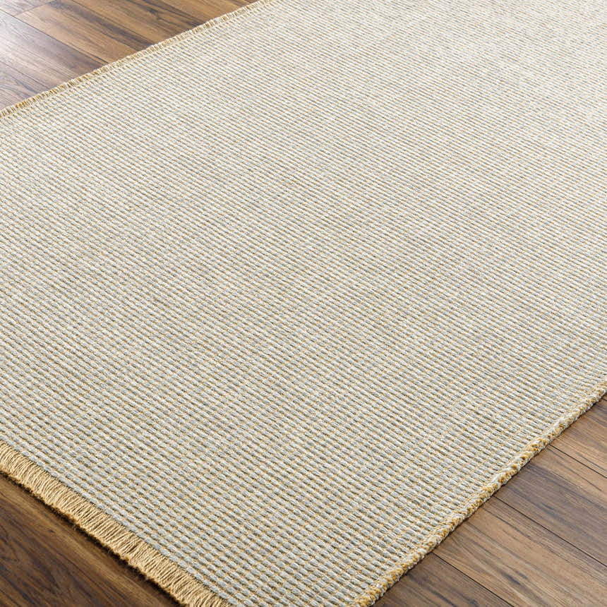 Close-up of the Kimi Becki Owens x LIVABLISS rug. Gray and light brown jute texture on wood floor. Corner