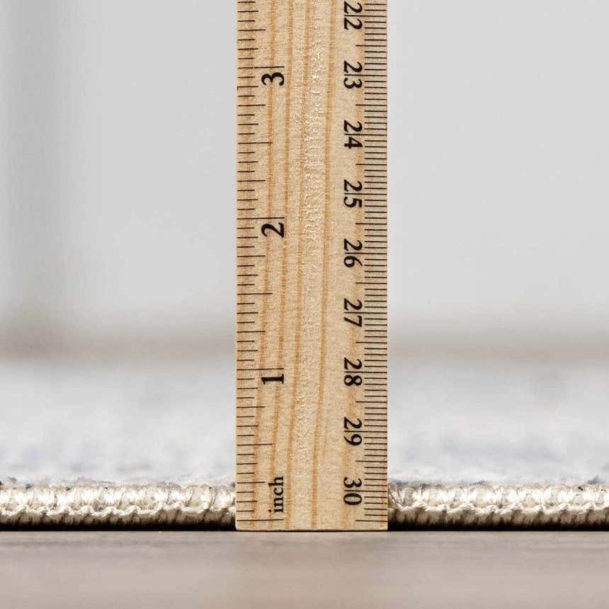 Close-up of the Lila Medallion Denim Area Rug pile height, showing its texture and construction with a ruler. Pile