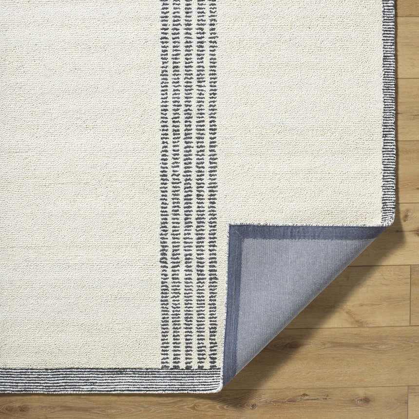 Close-up of the hand-tufted Ande Ivory Area Rug. Features light silver stripes on an off-white, wool texture. Fold