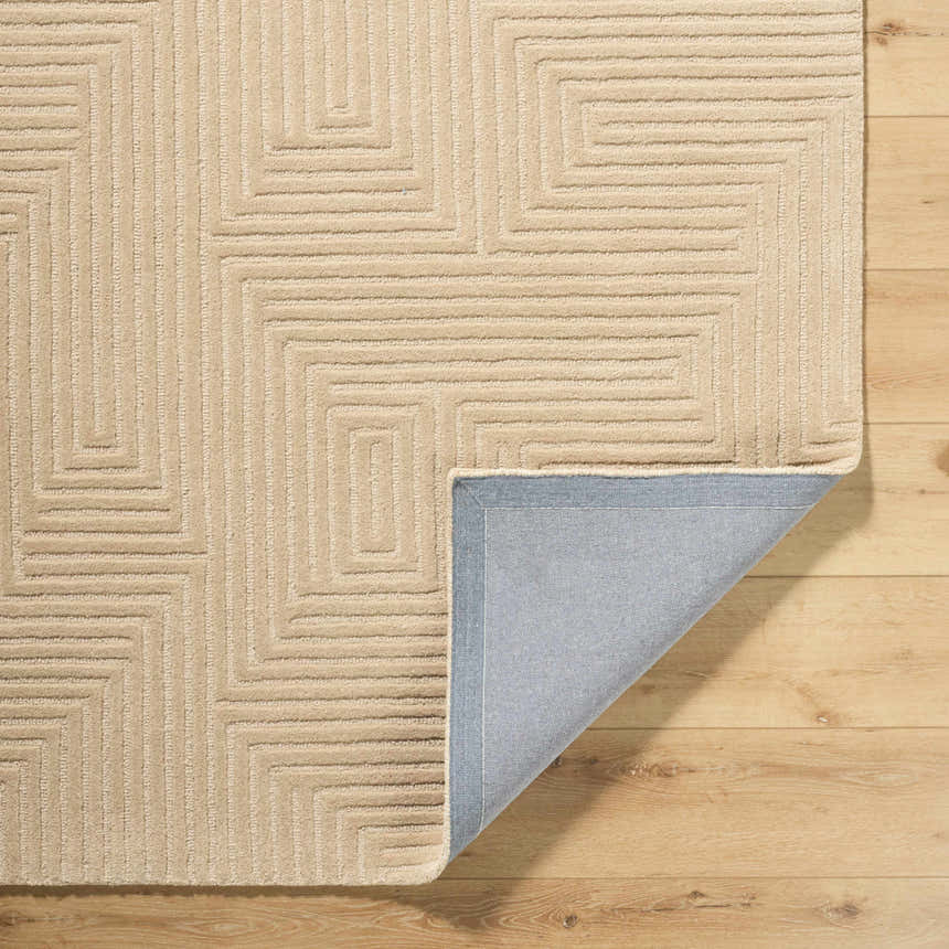 Close-up of the Citro Beige Area Rug showing its geometric pattern, wool texture, and backing on a wood floor. Fold