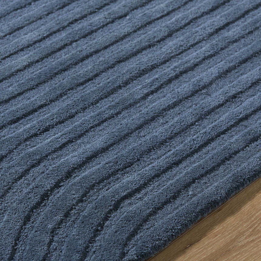 Close-up of the Whan Denim Area Rug showing its textured, striped design and soft, wool fibers. Texture