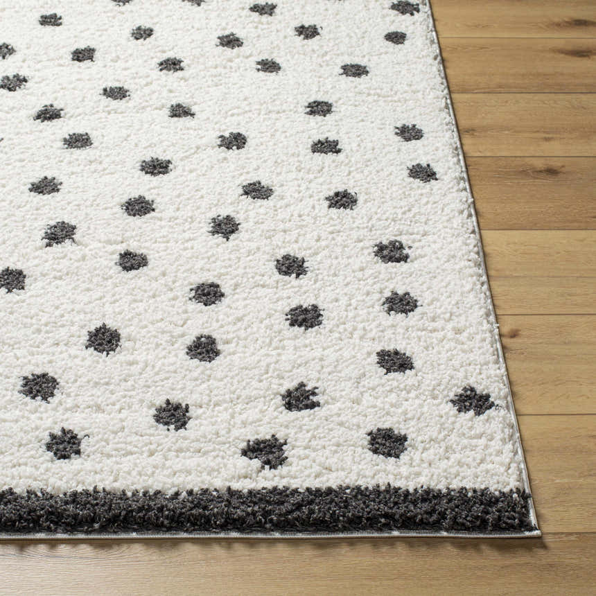 Close-up of Chaia Dotted Black & White Plush Rug. Soft, shag texture with black dots on a white background. Modern style. Front
