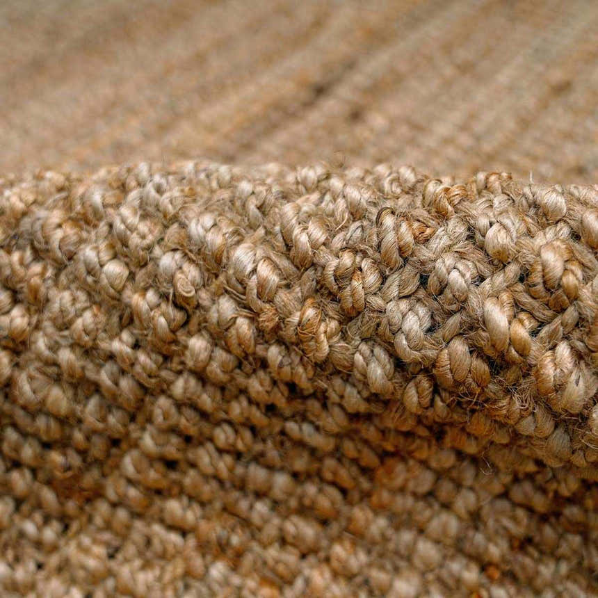 Close-up of the hand-woven texture of the Ambel Chocolate Brown Camel Jute Area Rug. Natural jute fibers in brown and beige tones. Fold