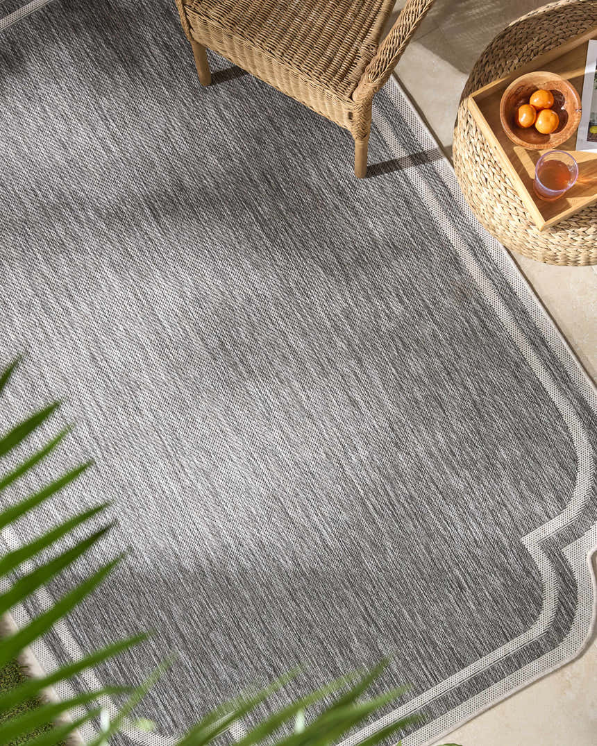 Outdoor patio scene with gray Arnola rug, wicker chair and table, and tropical plant. Roomscene-Rectangle