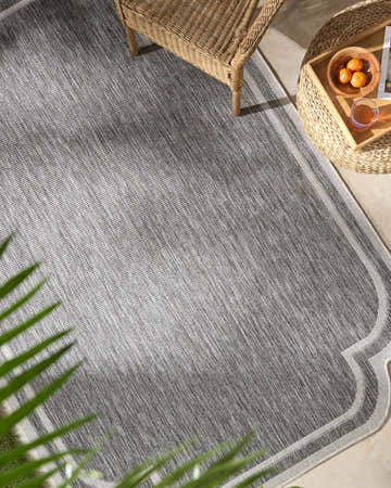 Outdoor patio scene with gray Arnola rug, wicker chair and table, and tropical plant. Roomscene-Rectangle