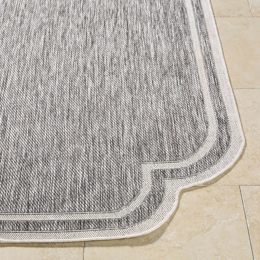 Close-up of Arnola Gray Outdoor Rug showing charcoal, cream, and gray woven texture and decorative edge. Front