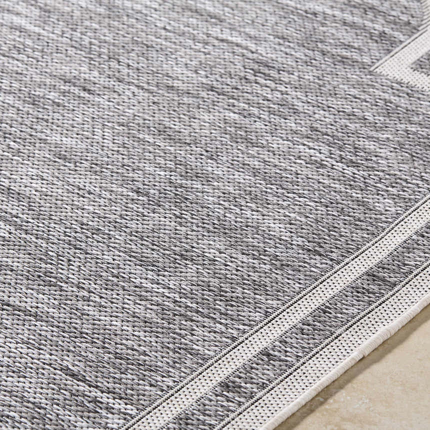 Close-up of Arnola Gray Outdoor Rug showing charcoal, cream, and gray woven texture and farmhouse style. Texture