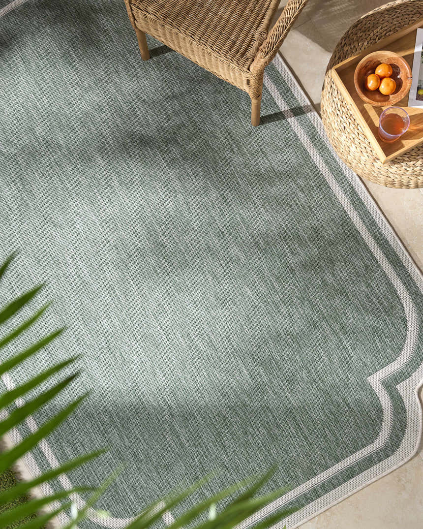 Outdoor patio scene with Arnola Green rug, wicker chair and table, and a tropical vibe. Roomscene-Rectangle