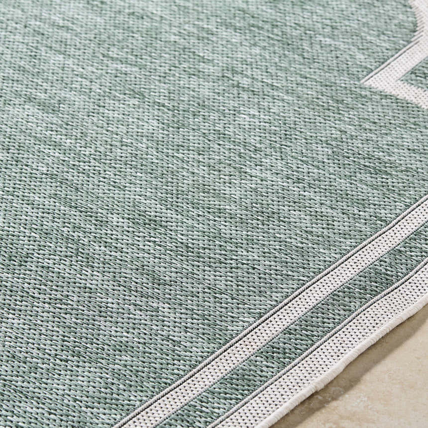 Close-up of the Arnola Green Outdoor Rug showing cream and green woven texture and runner edge detail. Texture