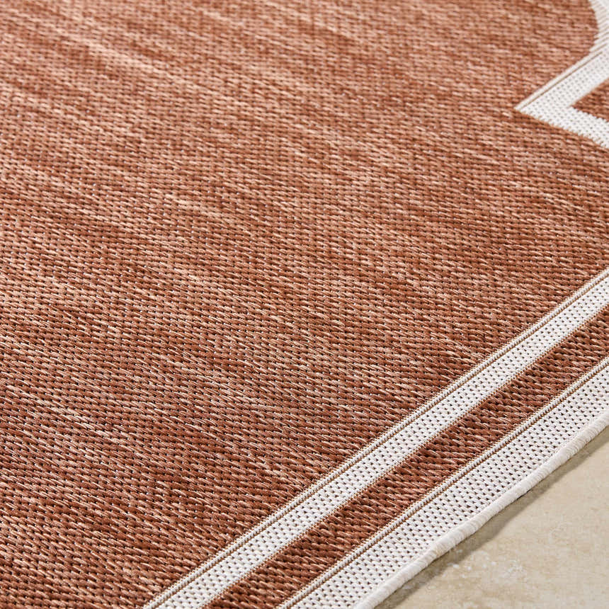 Close-up of the Arnola Brown Outdoor Rug, showing its woven texture and cream border detail. Texture