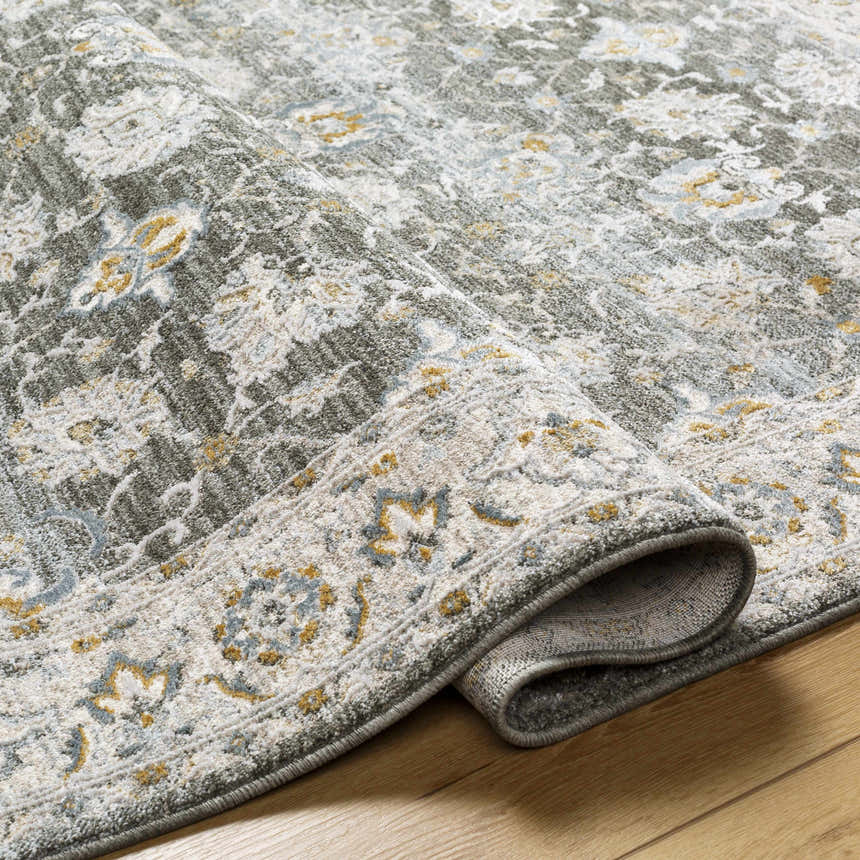 Close-up of the Amaru Green Textured Rug showing its floral pattern, texture, and colors like sage, gray, and mustard. Fold