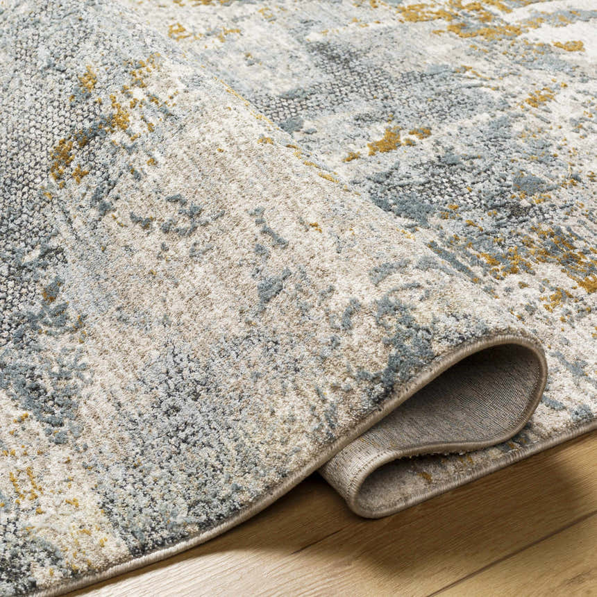 Close-up of Chaya Textured Abstract Rug. Features dusty sage, ink blue, light gray, and mustard hues. Machine woven texture. Fold